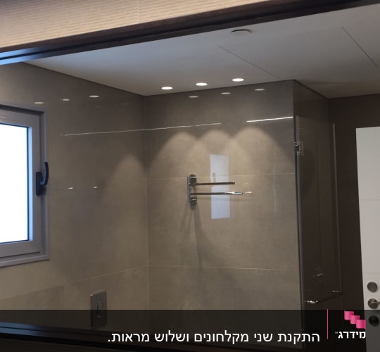 מראה גדולה עם מסגרת כהה בחדר אמבטיה